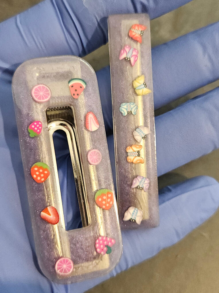 Purple hair clips, one with flowers and the other with butterflies Purple hair clips, one with flowers and the other with butterflies